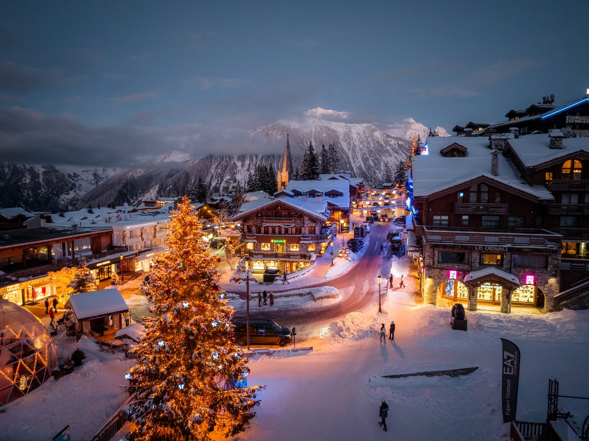 Courchevel 1850 at dusk, a lit Christmas tree in the snow-covered village square